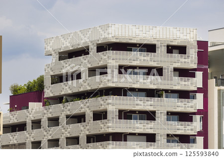 Modern apartment building with white grid covering balconies and purple facade Modern apartment building with white grid covering balconies and purple facade 125593840