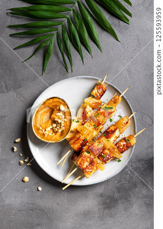Grilled tofu and pineapple satay skewers and peanut spicy sauce 125593959
