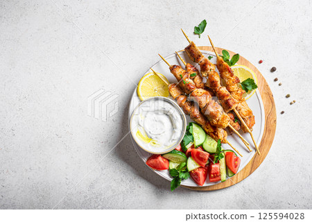 Grilled chicken kebabs with fresh vegetable salad and tzatziki sauce Grilled chicken kebabs with fresh vegetable salad and tzatziki sauce 125594028