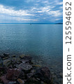 Serene waterscape with sailboat gliding under a soft sky, calm sailing ambiance with tranquil reflections 125594652