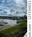 Scenic view of a lake with boats, docks, and mountains under a cloudy sky 125594653