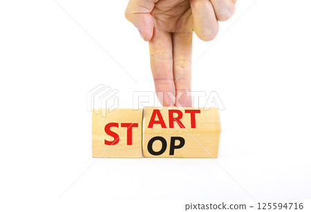 Start or stop symbol. Concept words Start or Stop on beautiful wooden block. Beautiful white table white background. Businessman hand. Business start or stop concept. Copy space. Start or stop symbol. Concept words Start or Stop on beautiful wooden block. Beautiful white table white background. Businessman hand. Business start or stop concept. Copy space. 125594716