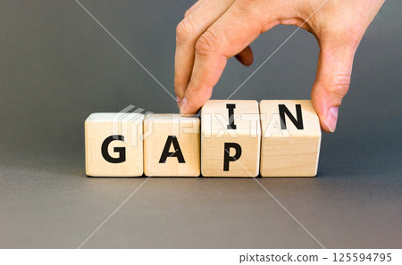 Gain or gap symbol. Concept words Gain Gap on wooden block. Beautiful grey table grey background. Businessman hand. Business gain or gap concept. Copy space. Gain or gap symbol. Concept words Gain Gap on wooden block. Beautiful grey table grey background. Businessman hand. Business gain or gap concept. Copy space. 125594795