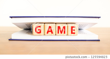Game symbol. Concept word Game on beautiful wooden blocks in book. Beautiful wooden table white background. Business, lifestyle and game concept. Copy space. Game symbol. Concept word Game on beautiful wooden blocks in book. Beautiful wooden table white background. Business, lifestyle and game concept. Copy space. 125594823