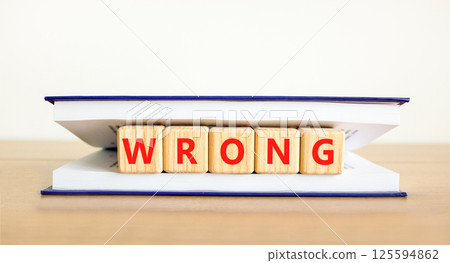 Wrong symbol. Concept word Wrong on beautiful wooden blocks in book. Beautiful wooden table white background. Business lifestyle wrong concept. Copy space. 125594862