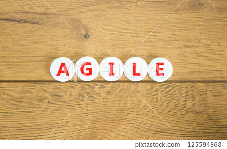 Agile symbol. Concept word Agile on beautiful white pills circles. Beautiful wooden table wooden background. Business flexible and agile concept. Copy space. 125594868