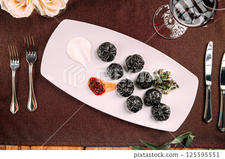 Gourmet black colored dumplings with sauce 125595551