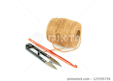 Ball of hemp rope, crochet hook and scissors isolated on white. 125595738