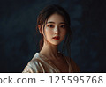 Photo portrait of a beautiful looking Asian girl with brown hair gathered in a ponytail and red lipstick on her lips 125595768
