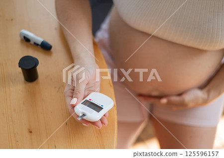 Pregnant woman doing home blood sugar test. Gestational diabetes.  125596157