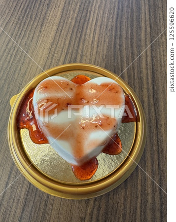 Strawberry-glazed heart dessert on wooden table top 125596620