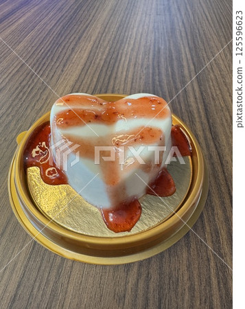 Heart-shaped dessert with strawberry sauce on wooden table 125596623