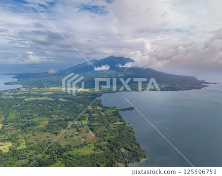 Aerial view of lush landscape featuring volcano near tranquil lake on a cloudy day 125596751