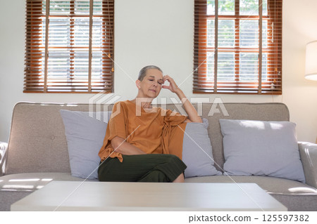 Elderly Woman Relaxing on Sofa in Sunlit Living Room with Wooden Blinds and Cozy Atmosphere Elderly Woman Relaxing on Sofa in Sunlit Living Room with Wooden Blinds and Cozy Atmosphere 125597382