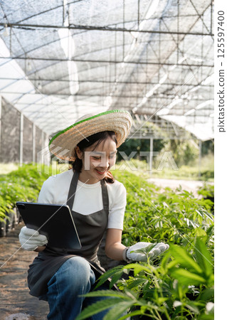 Young Woman Cultivating a Herbal Garden with Modern Technology and Sustainable Practices 125597400