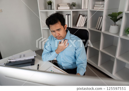 Office Worker Feeling Unwell at Desk with Cold Symptoms in Modern Workplace Environment Office Worker Feeling Unwell at Desk with Cold Symptoms in Modern Workplace Environment 125597551