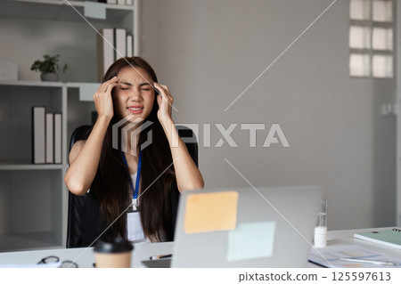 Young Businesswoman Experiencing Stress and Fatigue at Work in Modern Office Environment 125597613