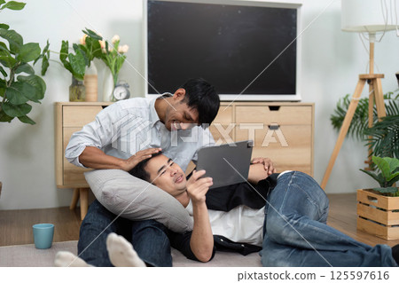 Affection and Relaxation. Two men enjoying a cozy moment while using a tablet at home. Affection and Relaxation. Two men enjoying a cozy moment while using a tablet at home. 125597616