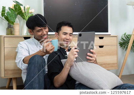 LGBTQ Togetherness and Joy. Two men enjoying a light-hearted moment while using a tablet. 125597617