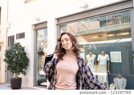 Stylish woman with shopping bags walking outside a fashion boutique, enjoying a shopping day in the city. Stylish woman with shopping bags walking outside a fashion boutique, enjoying a shopping day in the city. 125597769
