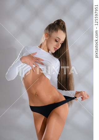 Sporty woman showcasing fitness in a sleek outfit during a studio session 125597951