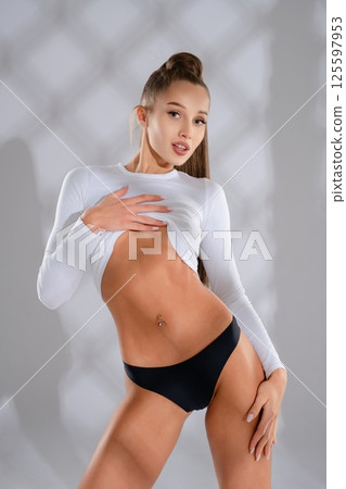 Woman showcasing athletic beauty in stylish sport attire indoors Woman showcasing athletic beauty in stylish sport attire indoors 125597953