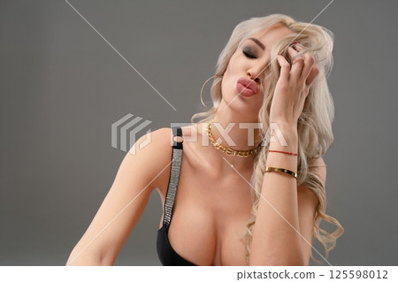 Elegant woman poses confidently in stylish lingerie against a neutral backdrop Elegant woman poses confidently in stylish lingerie against a neutral backdrop 125598012