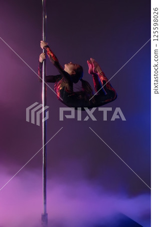 Young girl performing a stunning pole dance routine with vibrant fabric 125598026