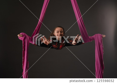 Girl performing aerial sport with pink fabric during indoor session 125598032