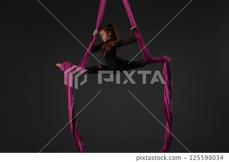 Girl performing an impressive aerial routine with pink fabric 125598034