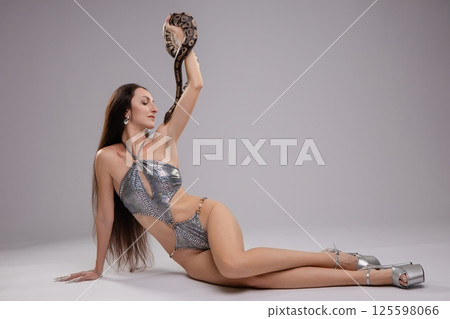 Woman in lingerie poses with a snake in a minimalist studio setting 125598066