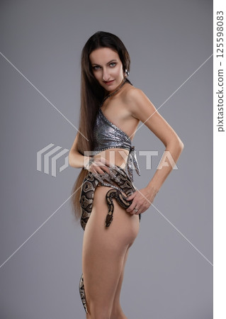Elegant woman posing with a snake while wearing lingerie in a studio setting Elegant woman posing with a snake while wearing lingerie in a studio setting 125598083