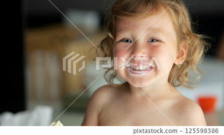 Cheerful preschooler girl enjoys ice cream with big smile 125598386