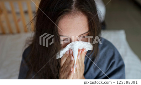 Sick woman blowing nose in hotel room 125598391