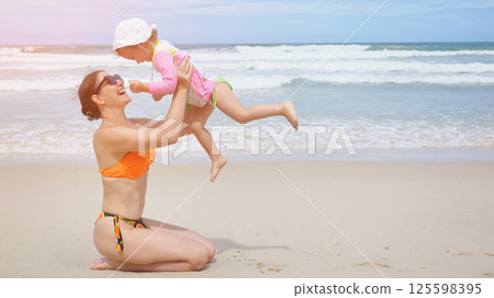 Mother and daughter playing on the beach 125598395