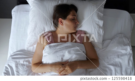 Woman tossing and turning in bed having trouble sleeping Woman tossing and turning in bed having trouble sleeping 125598418