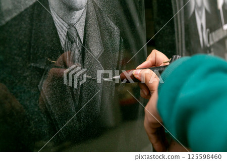 The hand of a female artist who applies images to monuments by hand engraving. The hand of a female artist who applies images to monuments by hand engraving. 125598460