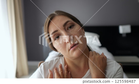Woman suffering neck pain in hotel room 125598487