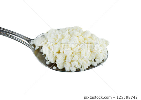 Close-up of metal spoon with fresh cottage cheese over white background. Close-up of metal spoon with fresh cottage cheese over white background. 125598742