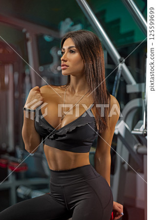 fit woman showcases her confidence in activewear while posing in gym. She highlights fitness and wellness inspiring others in vibrant workout environment. fit woman showcases her confidence in activewear while posing in gym. She highlights fitness and wellness inspiring others in vibrant workout environment. 125599699