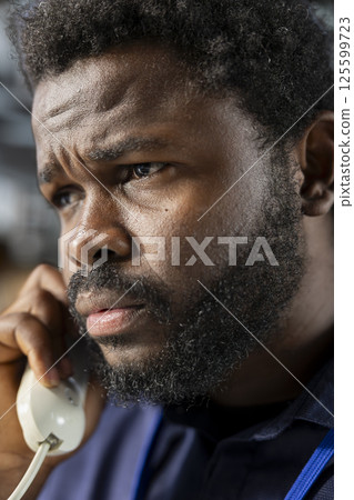 African american employee using the office landline phone to stay connected with the other business departments, receiving a call to discuss about daily administrative tasks. Close up. 125599723