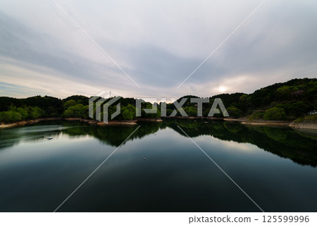 Fresh greenery at Nara Nunome Dam. Beautiful reflection of the cloudy sky and lake surface as the sun sets. Still image 23. 125599996