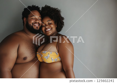 Couple sharing a joyful moment together with smiles while posing against a neutral background Couple sharing a joyful moment together with smiles while posing against a neutral background 125602241