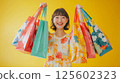 Happy young woman joyfully holds many colorful shopping bags. 125602323