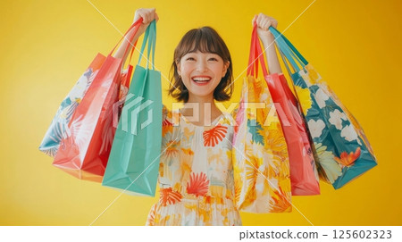 Happy young woman joyfully holds many colorful shopping bags. 125602323