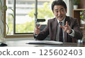 Confident mature businessman conducts a lively office meeting presentation. 125602403