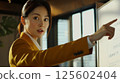 A focused businesswoman points to a whiteboard du a presentation in a modern office. 125602404