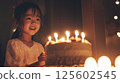 A happy little girl blows out candles on her birthday cake at night. 125602545