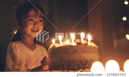 A happy little girl blows out candles on her birthday cake at night. A happy little girl blows out candles on her birthday cake at night. 125602545