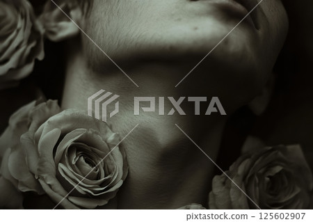 Close-up of a person with a relaxed expression surrounded by roses in a soft monochrome setting 125602907